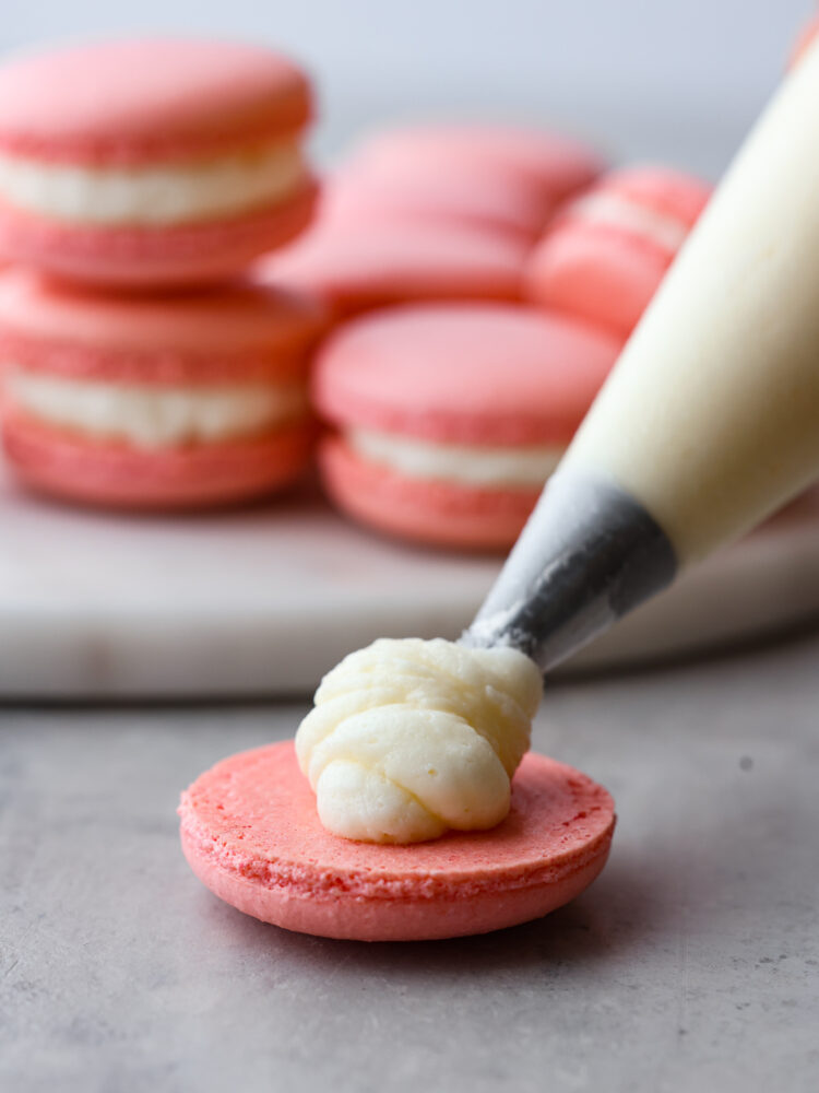 A photo showing the filling being piped onto one half of the cookie.