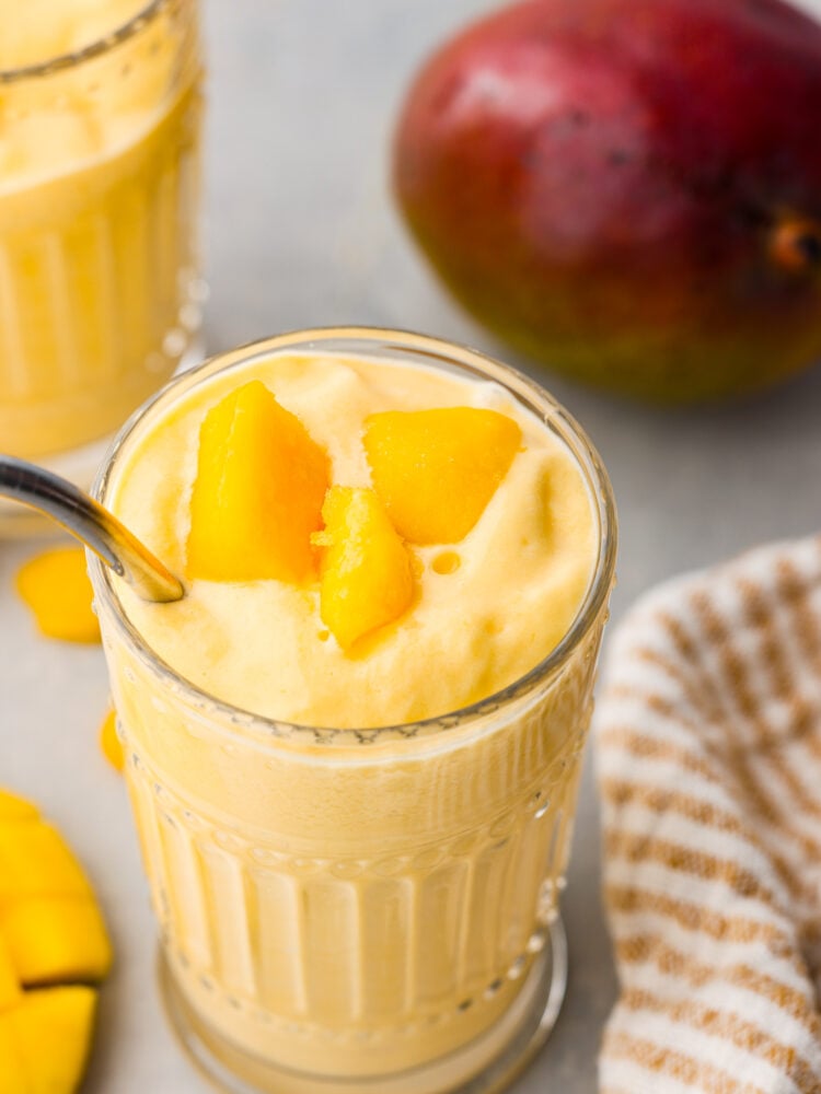 A top view of a mango lassi with a few chunks of mango on top.