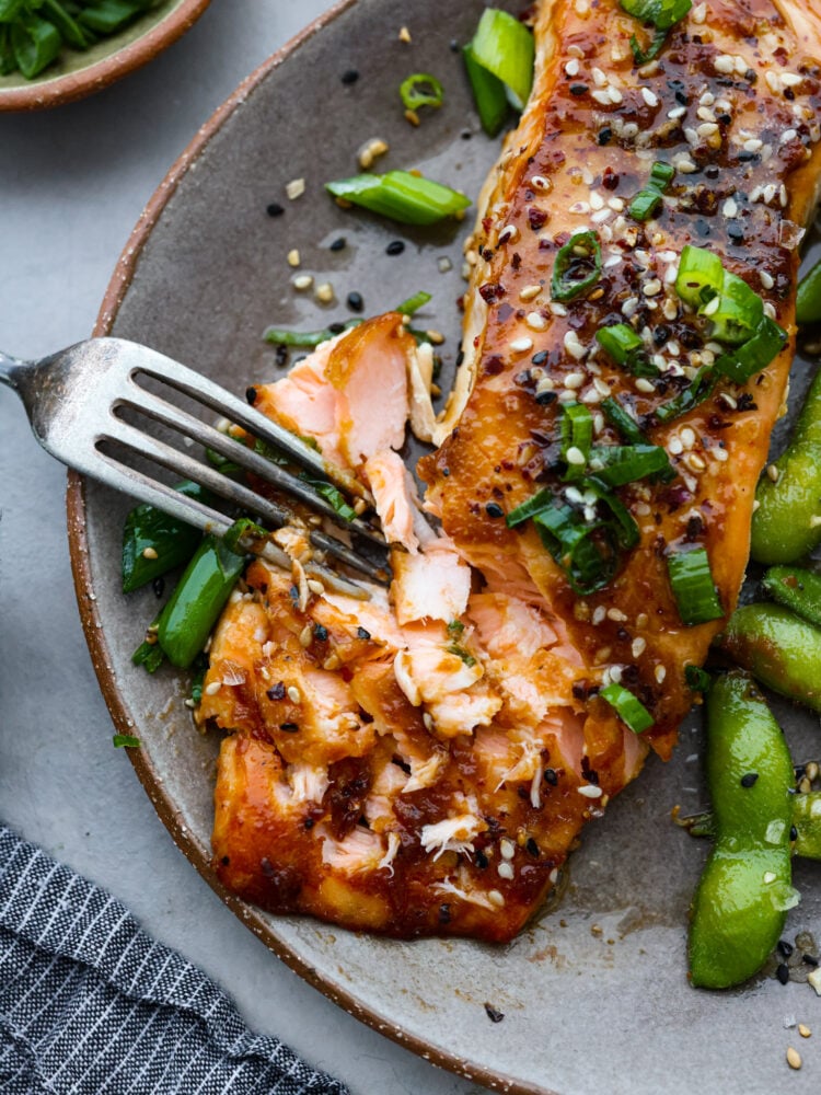 A fork pulling apart flaky miso glazed salmon.