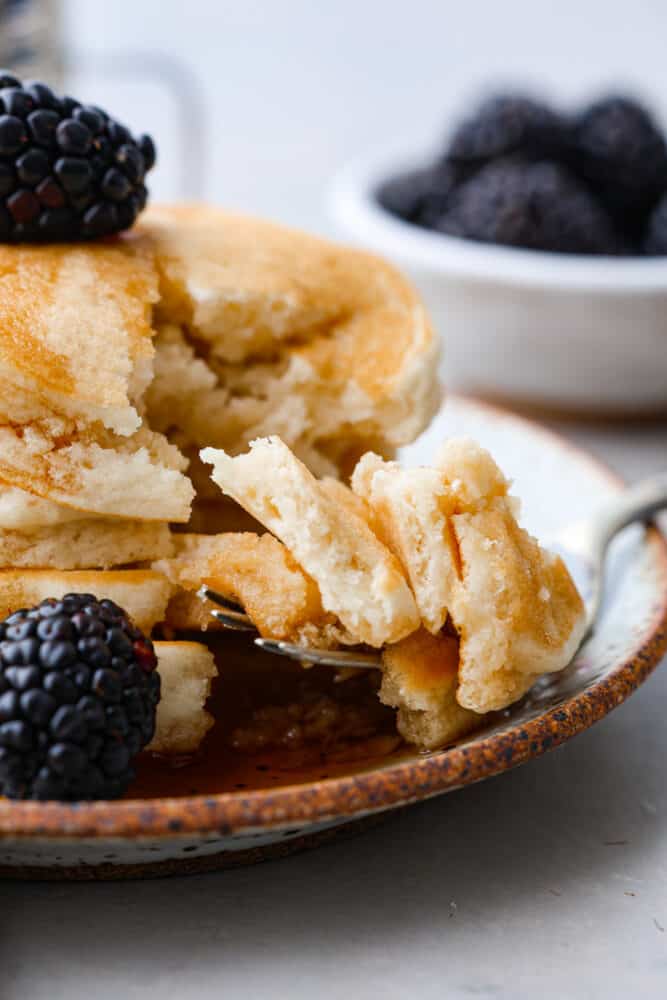 Closeup of a bite of pancake on a fork.