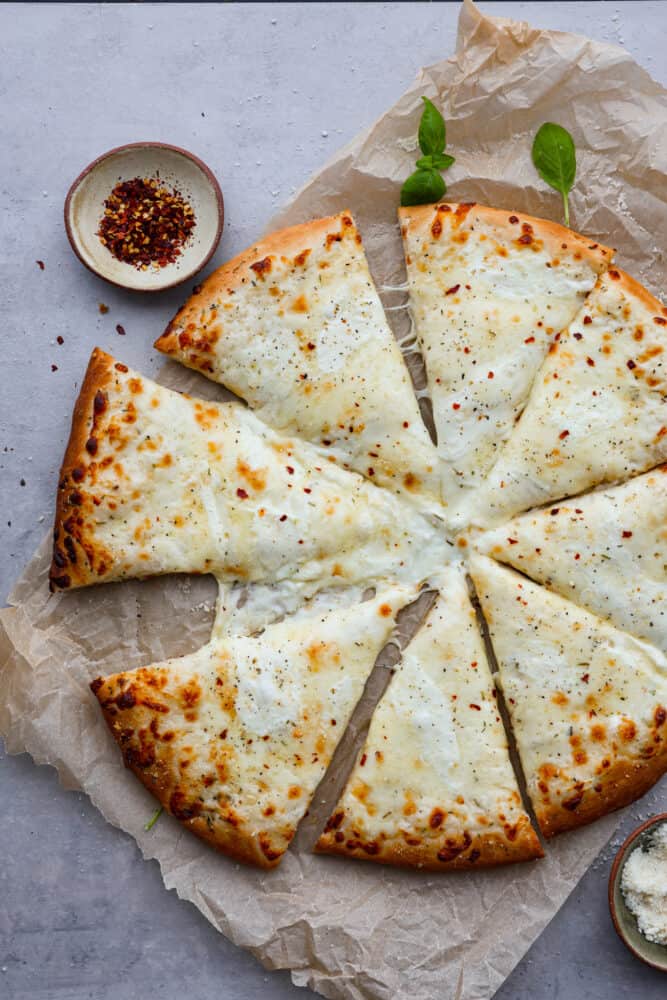 White pizza all sliced up on top of parchment paper.