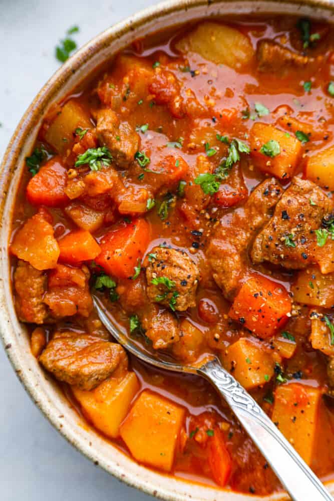 A close up on Hungarian goulash in a bowl with a spoon.