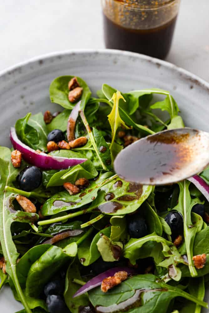 A spoon pouring the dressing over a salad.