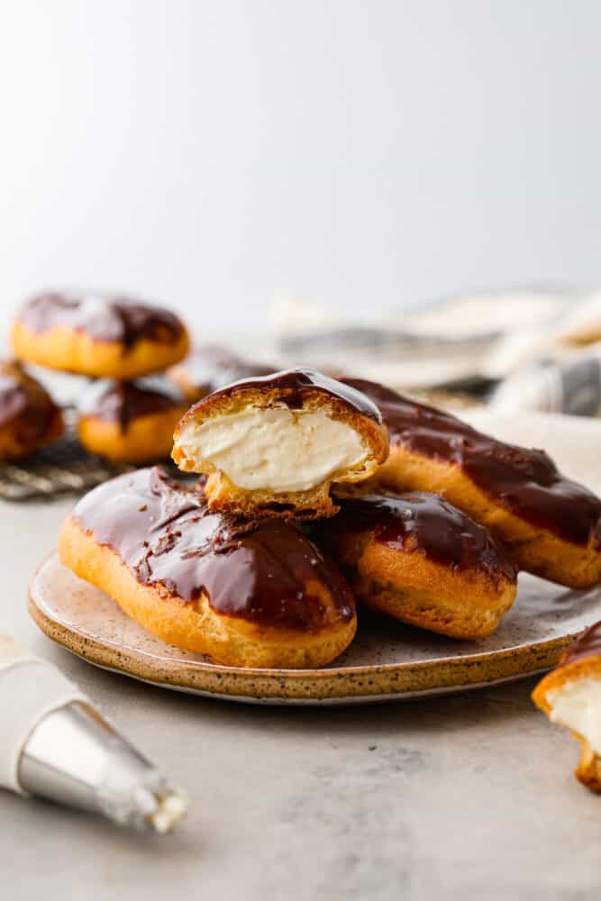 4 eclairs on a plate. One is cut in half.