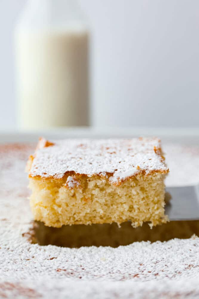 A piece of hot milk cake being pulled out of the cake.