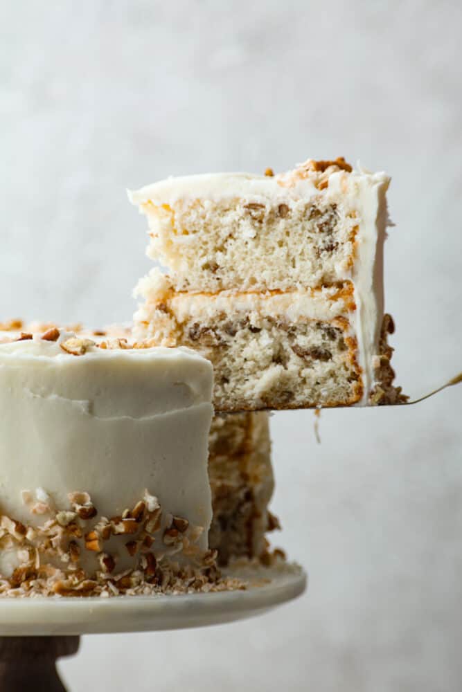 A slice of Italian cream cake being served with a cake spatula.