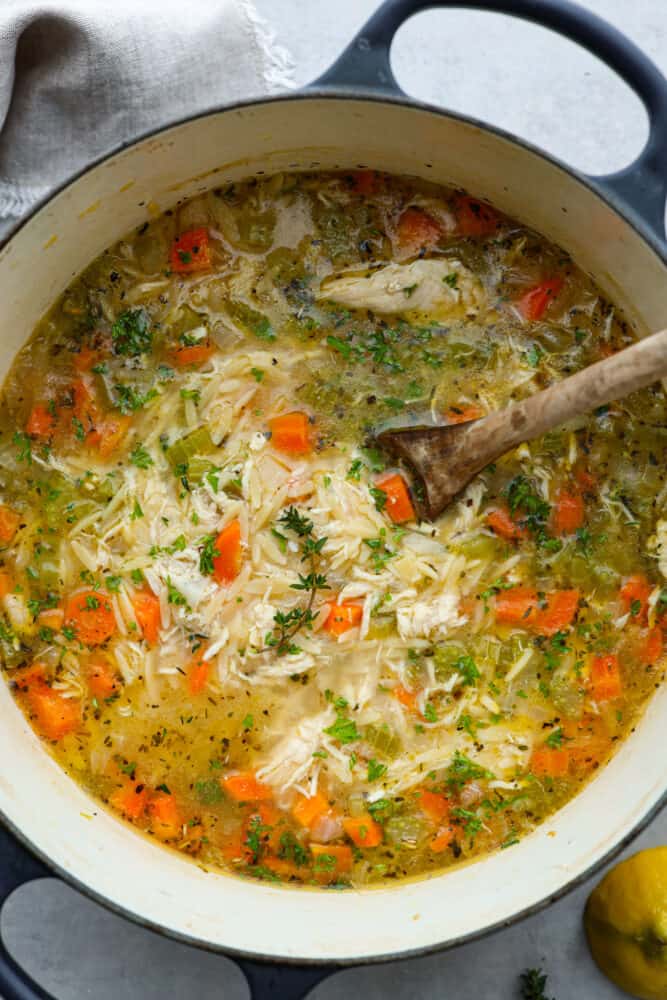 A look at the soup in a pot with a wooden spoon in it.