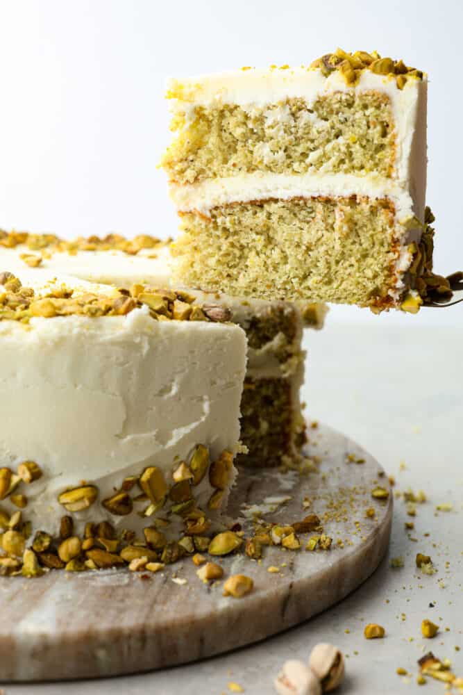 Pistachio cake slice being lifted up with a spatula.