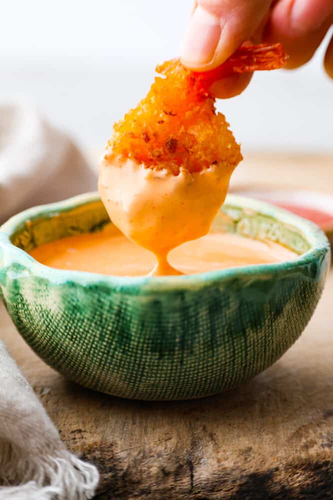 Dipping fried shrimp into sriracha mayo.