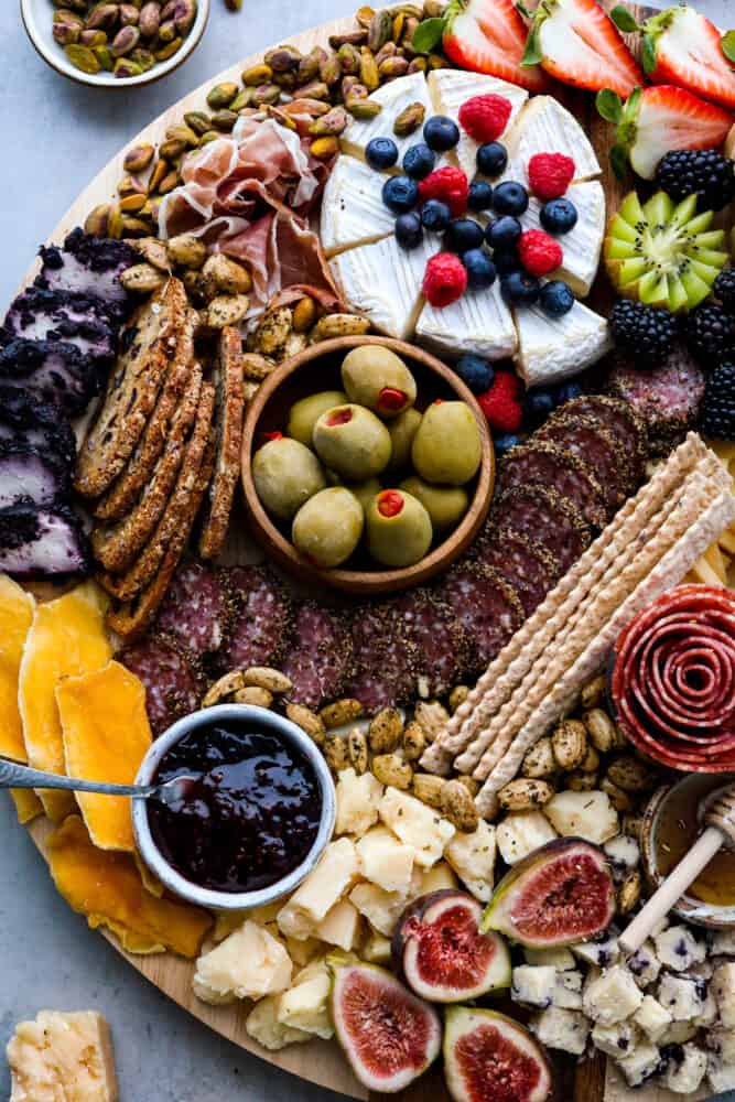 Closeup of various meats, cheeses, crackers, fruits, and spreads.