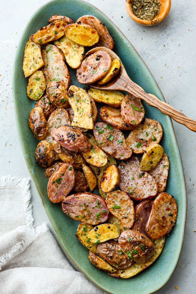 Fingerling potatoes on a plate with a wooden spoon.