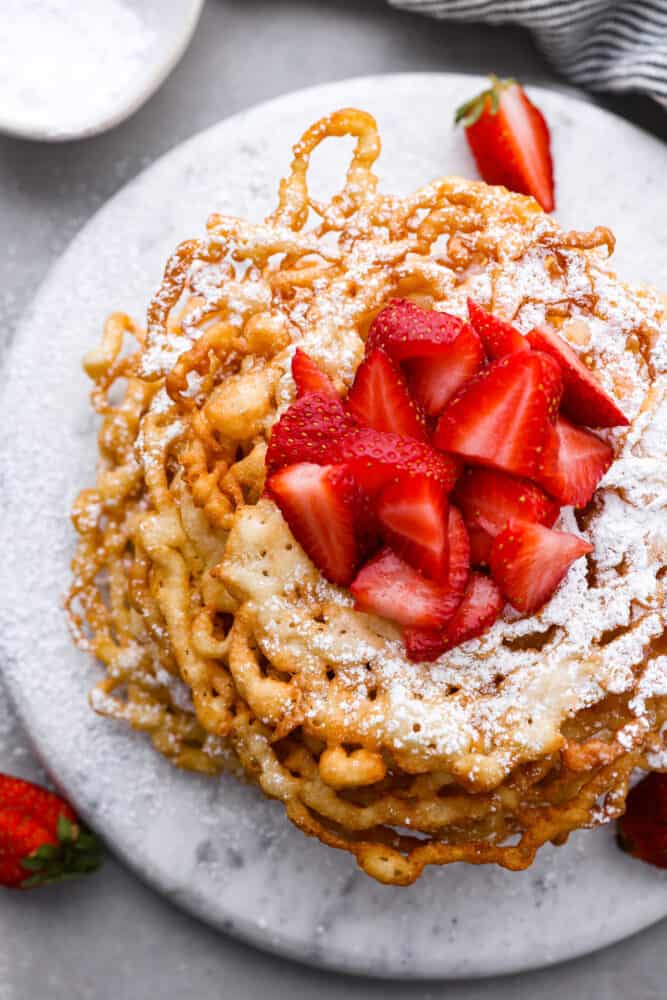 An overhead view of funnel cakes topped with straberries.