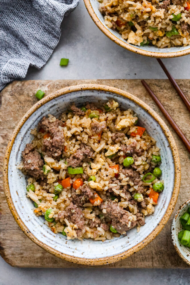 Beef fried rice in a bowl with chop sticks next to it.