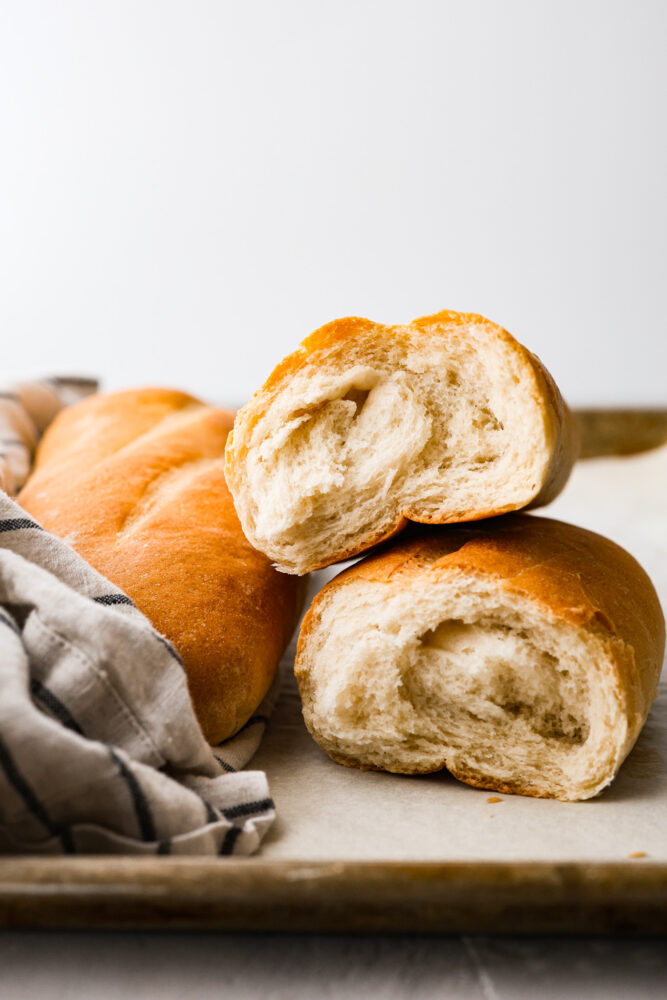 Italian bread ripped in half and stacked on top of each other showing the fluffy inside.