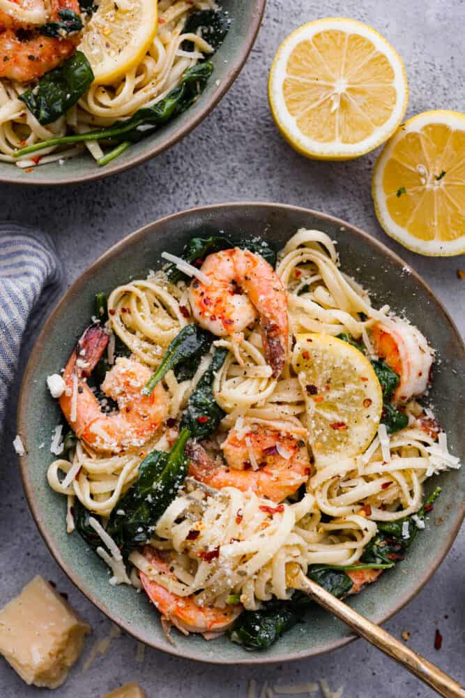 Lemon garlic parmesan shrimp pasta in a bowl with fresh lemon cut in half next to it.