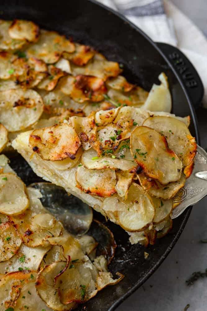 A slice of potato galette being lifted out of the cast iron skillet.