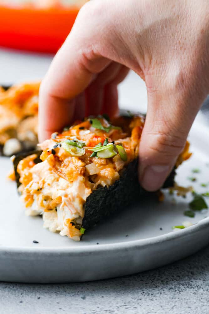 A hand wrapping nori around the sushi bake.