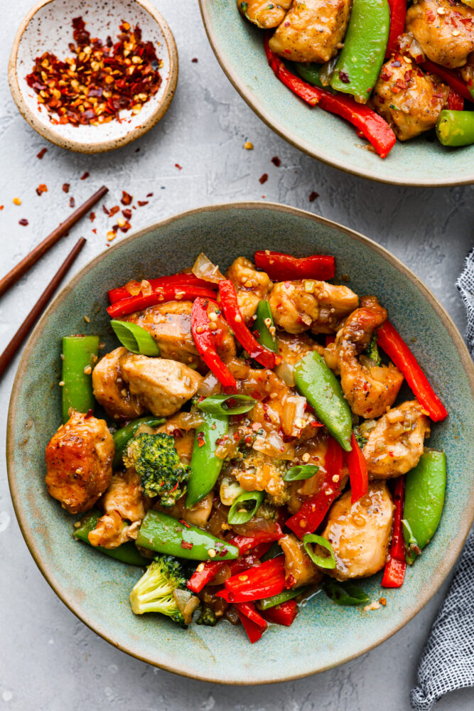 Top-down view of Szechuan chicken served in a blue-green bowl.