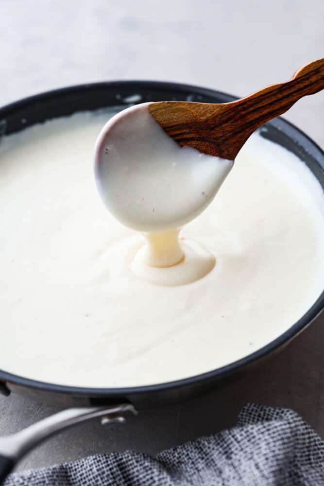 Hero image of bechamel sauce in a black saucepan.