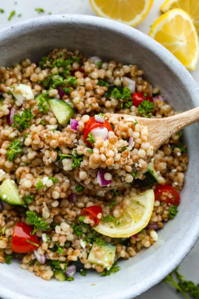 Scooping up salad with a wooden spoon.