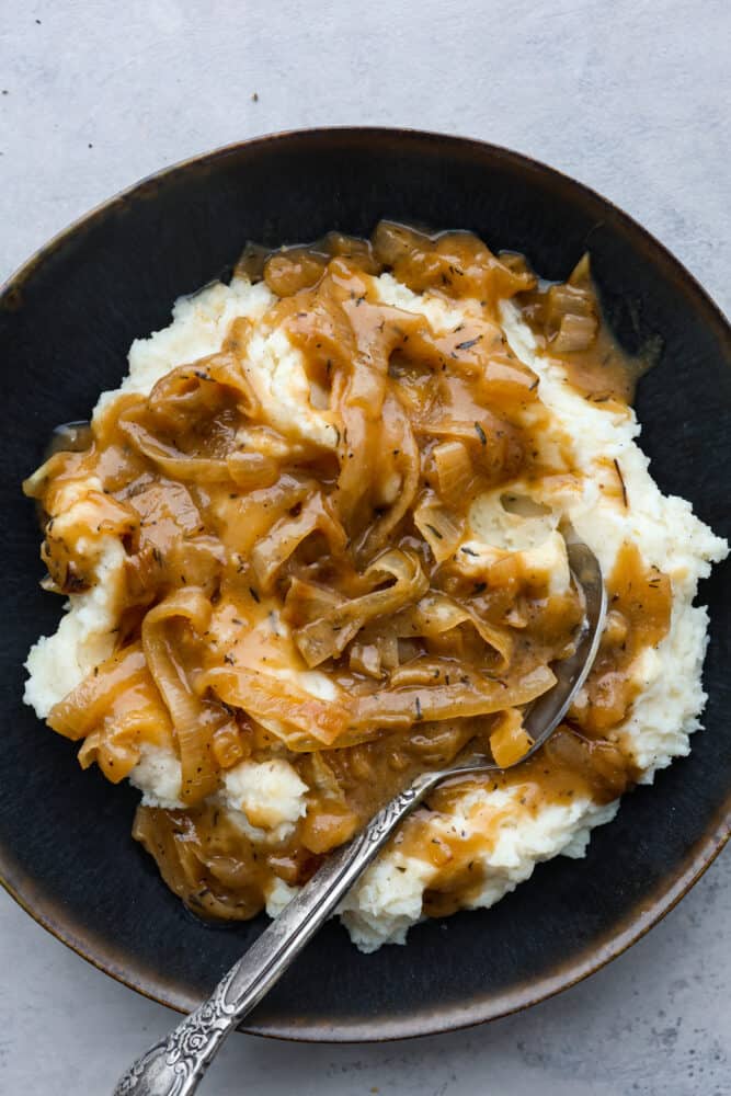 Gravy served over mashed potatoes in a black dish.