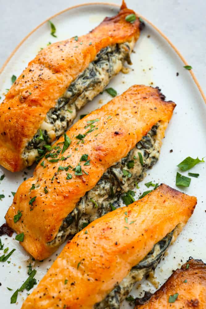 3 stuffed salmon filets on a white plate.