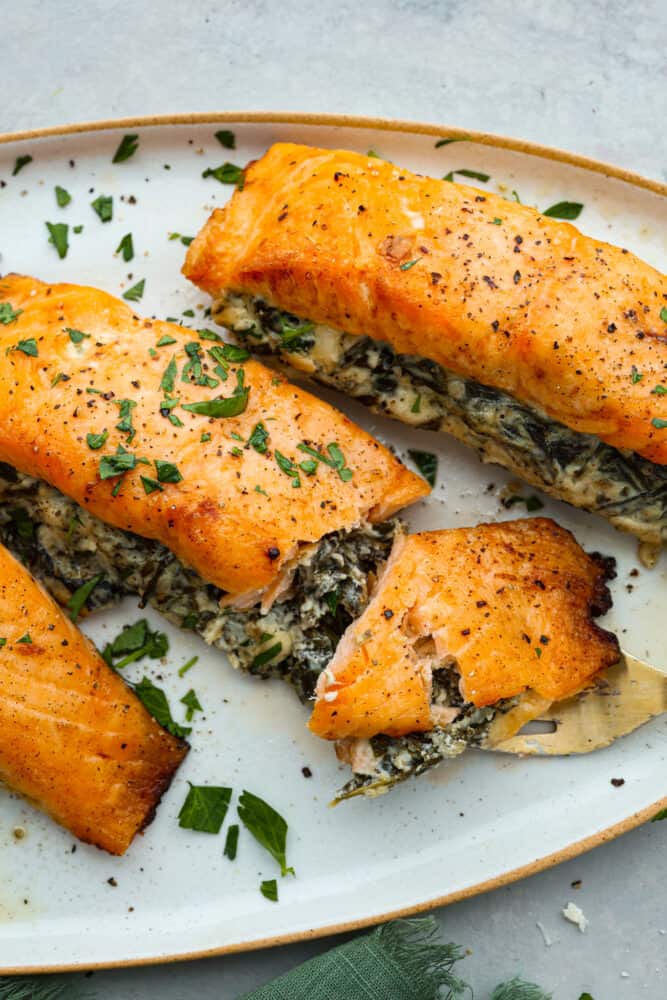 Closeup of stuffed salmon with a bite taken out of it, so the cream cheese spinach filling can be seen.