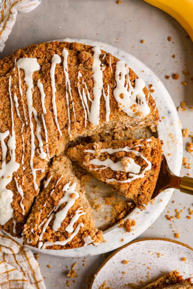 Top-down view of banana coffee cake, with a slice being served with a cake spatula.