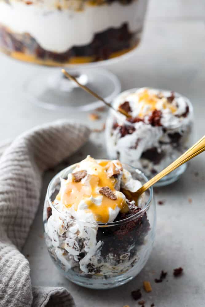 Chocolate cake, whipped cream, and caramel served in small glasses.