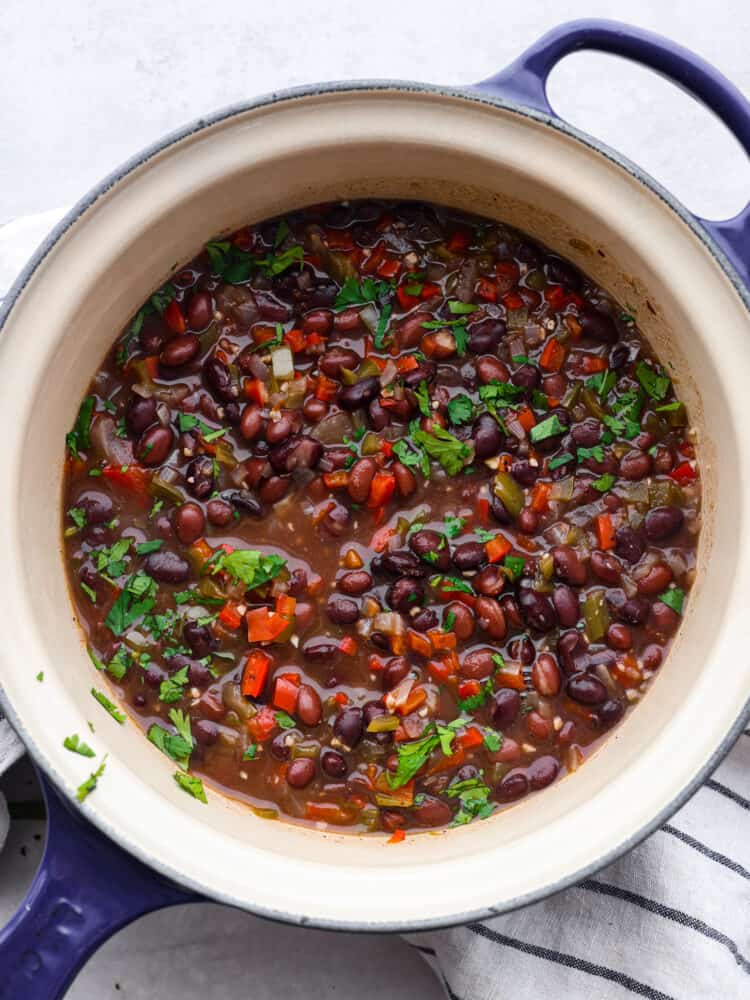 Top-down view of beans and chopped vegetables in a blue and white pot.