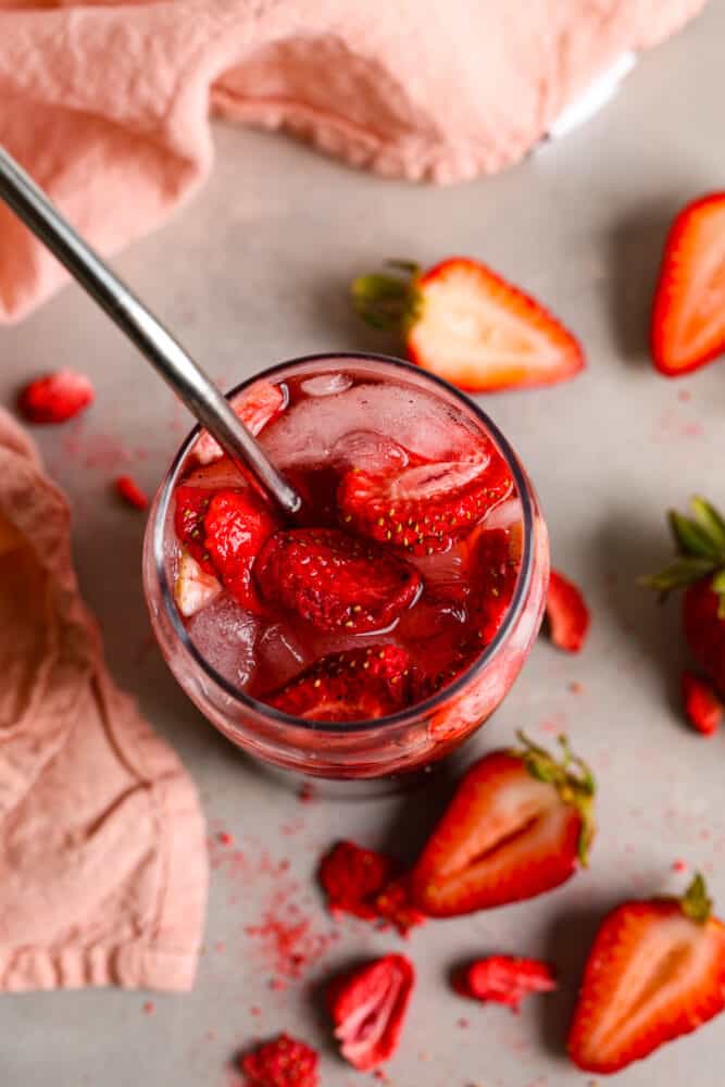 The top view of a strawberry acai refresher. You can see into the cup with ice and strawberries at the top. 