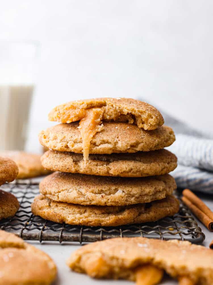 5 snickerdoodles stacked on top of each other. There is a bite taken out of one of them so the caramel filling can be seen.