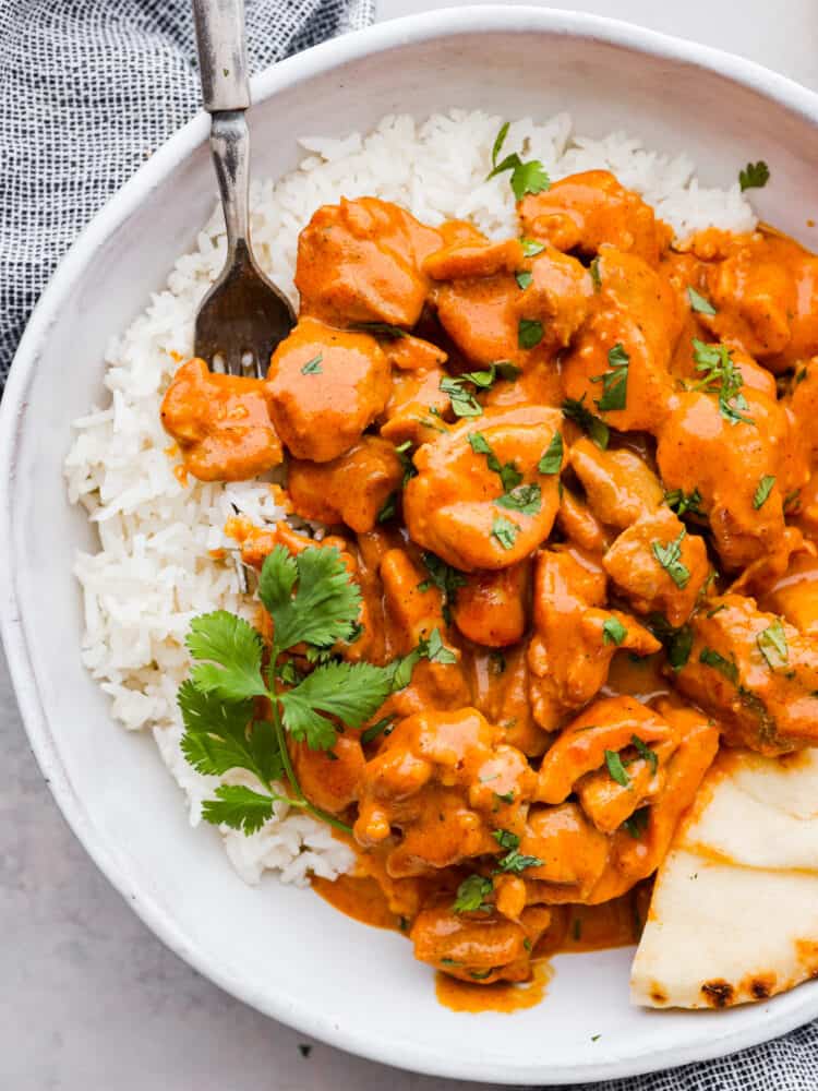 Closeup of butter chicken in a white bowl.