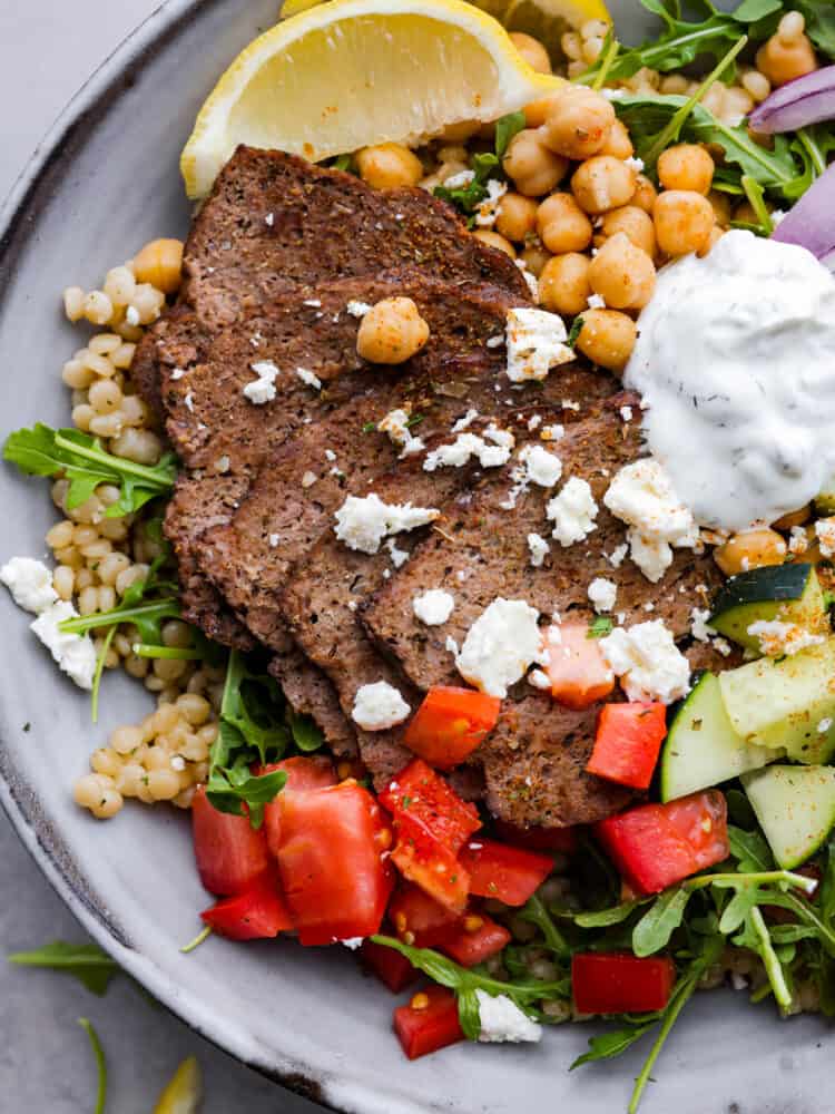 Closeup of gyro meat, topped with feta cheese and tzatziki sauce.