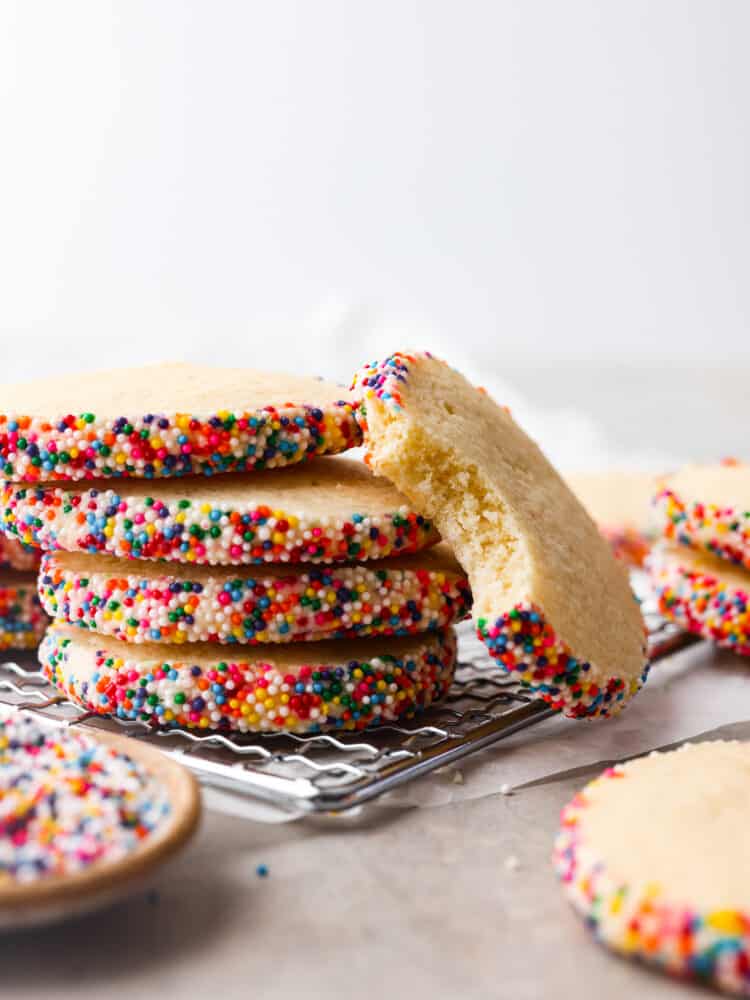 A stack of 4 cookies. One cookie is laying up against them with a bite taken out of it.