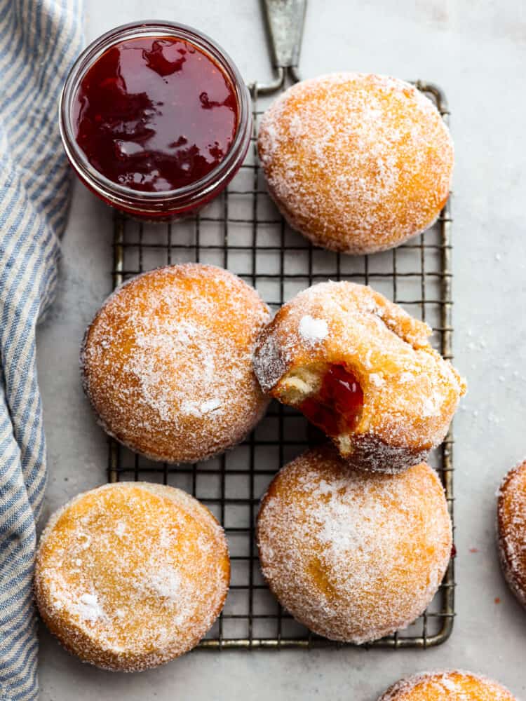 5 jelly donuts on a cooling rack.