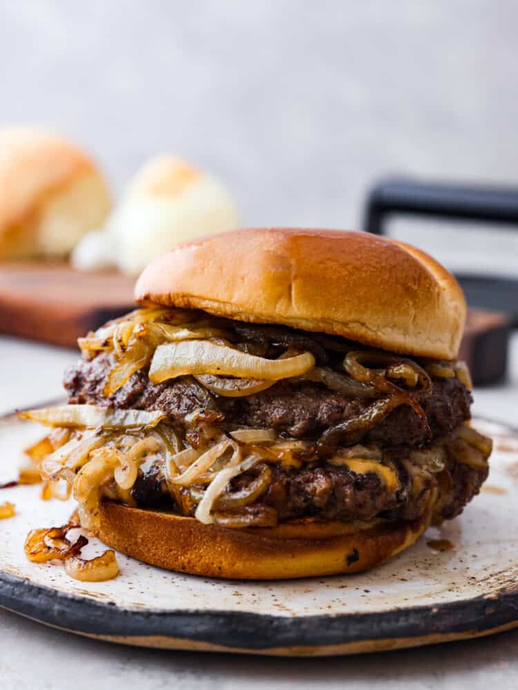 An onion smash burger on a stoneware plate.