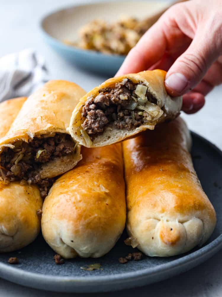 Runzas stacked on top of each other. One is cut in half so you can see the filling.