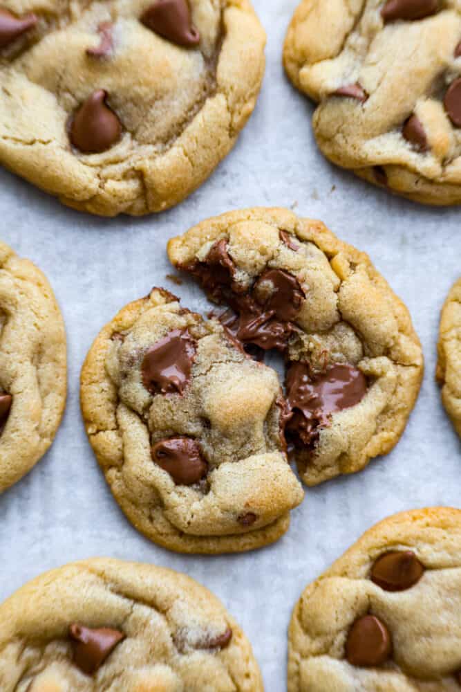 A chocolate chip cookie that is split open on parchment paper. 