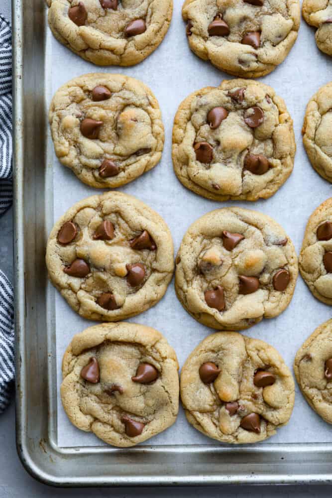 Chocolate chip cookies baked on parchment paper on a baking sheet. 