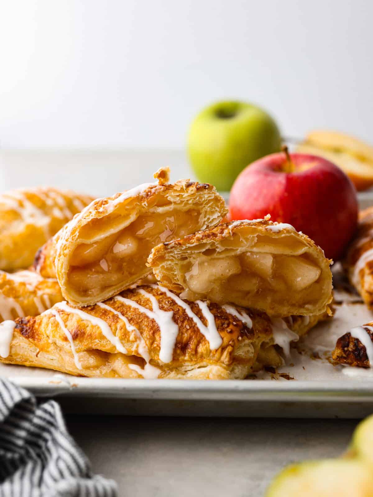 2 apple turnovers stacked on on another. the top one is cut open so that you can see the filling. 