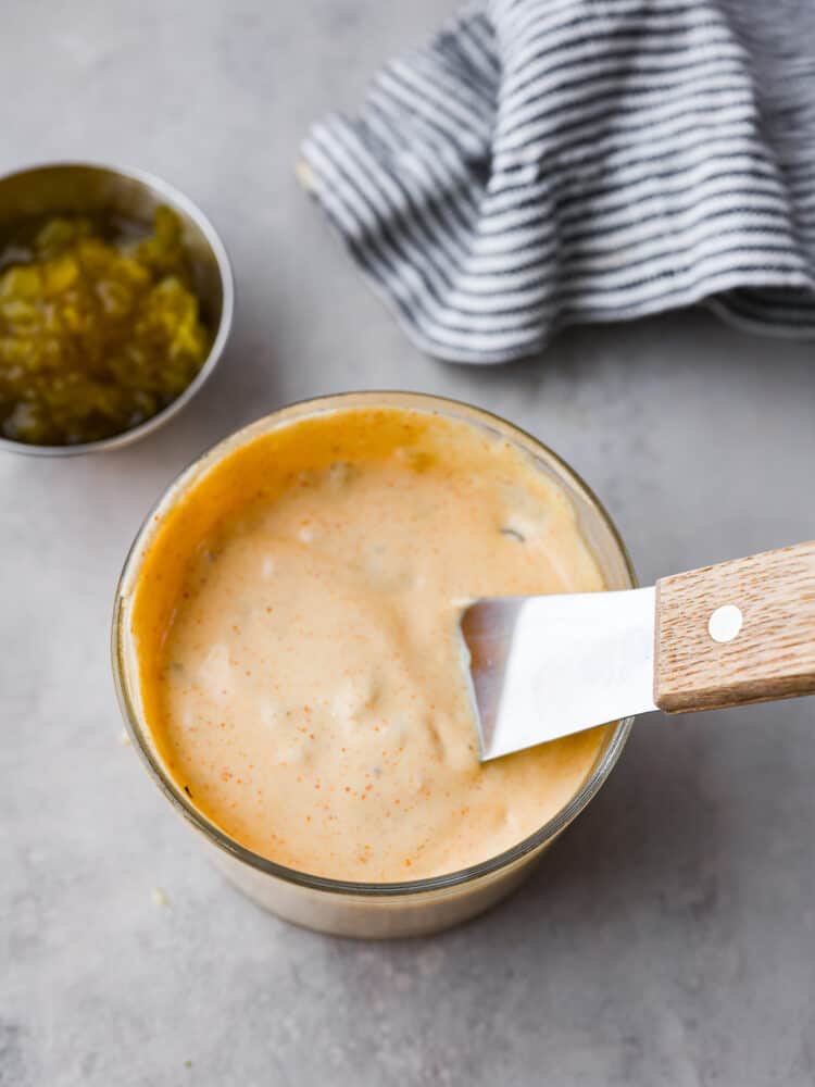 Top-down view of big mac sauce container with a small serving spatula in it.