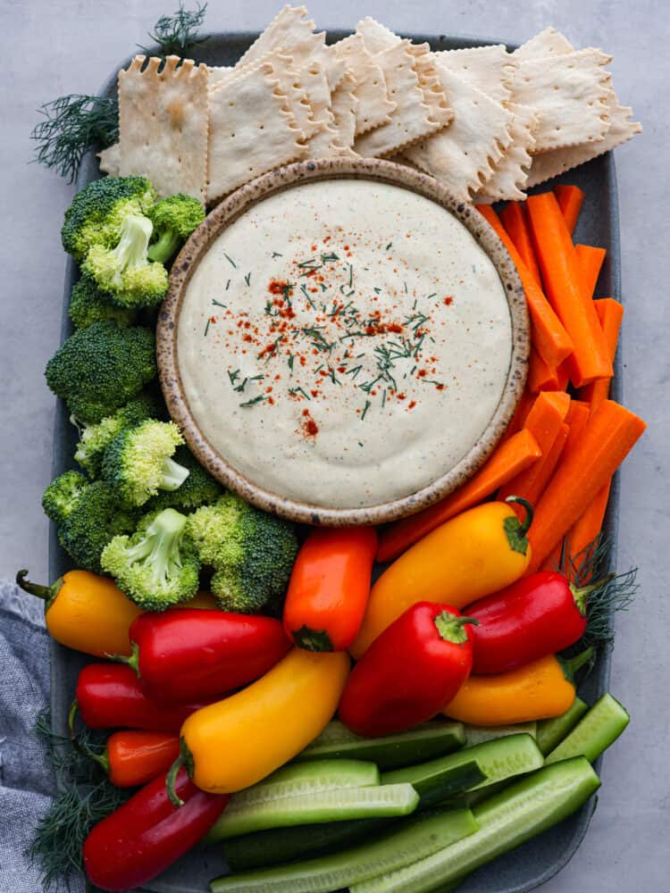 Cottage cheese dip on a serving board with vegetables and crackers.