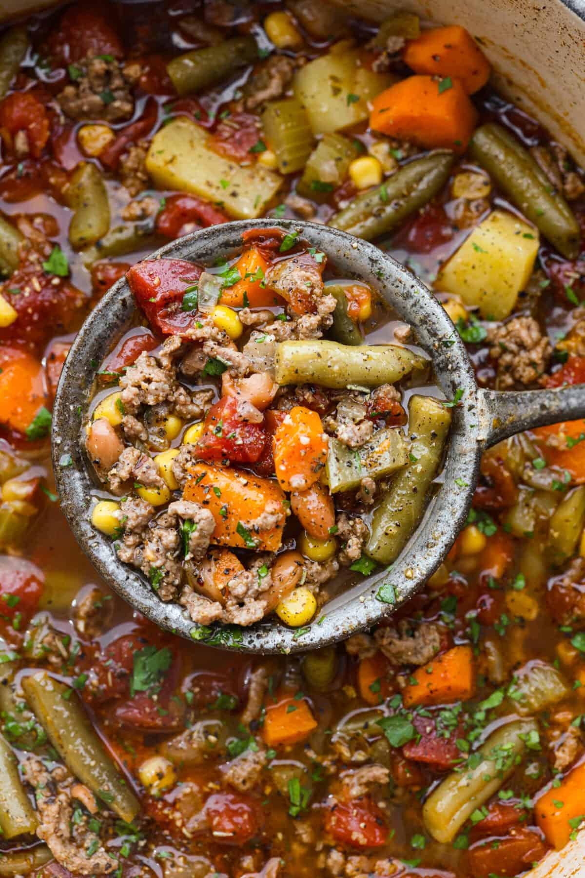 A close up of hamburger soup in a ladle. 