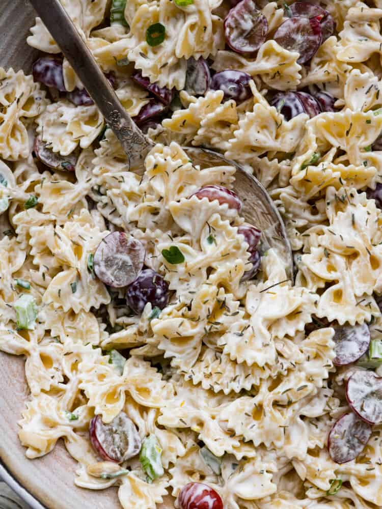 A closeup of lemon tarragon pasta salad with a large silver spoon. 