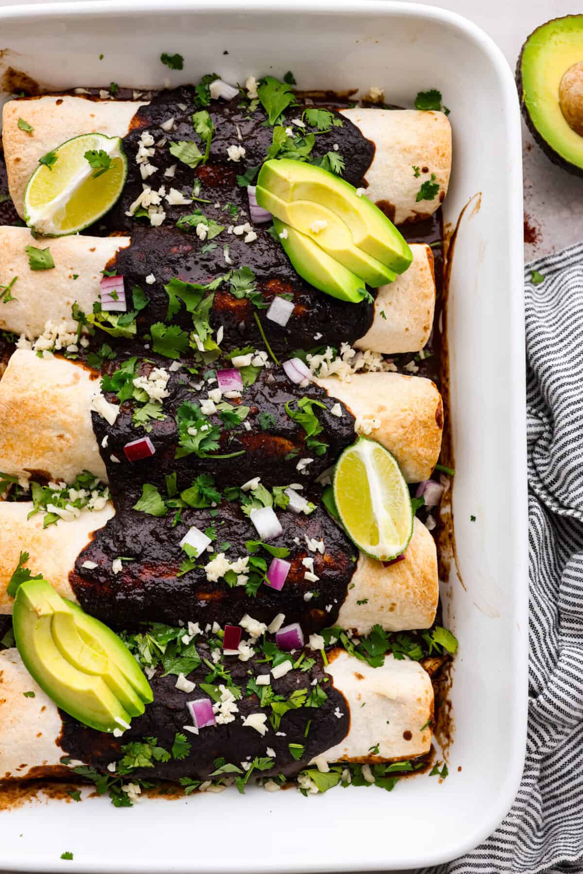 Top-down view of baked enchiladas in a white casserole dish.