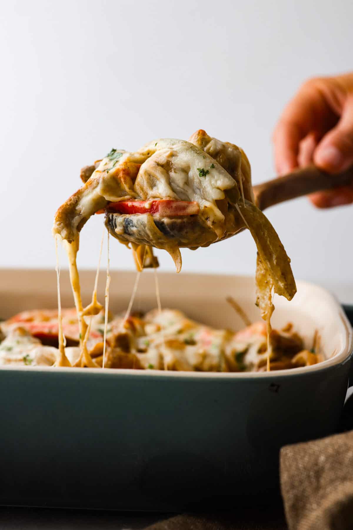 The side view of a spoon scooping out Philly cheesesteak casserole. 