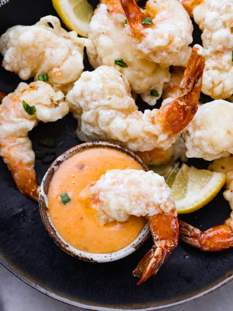 A piece of shrimp being dipped in the sauce.