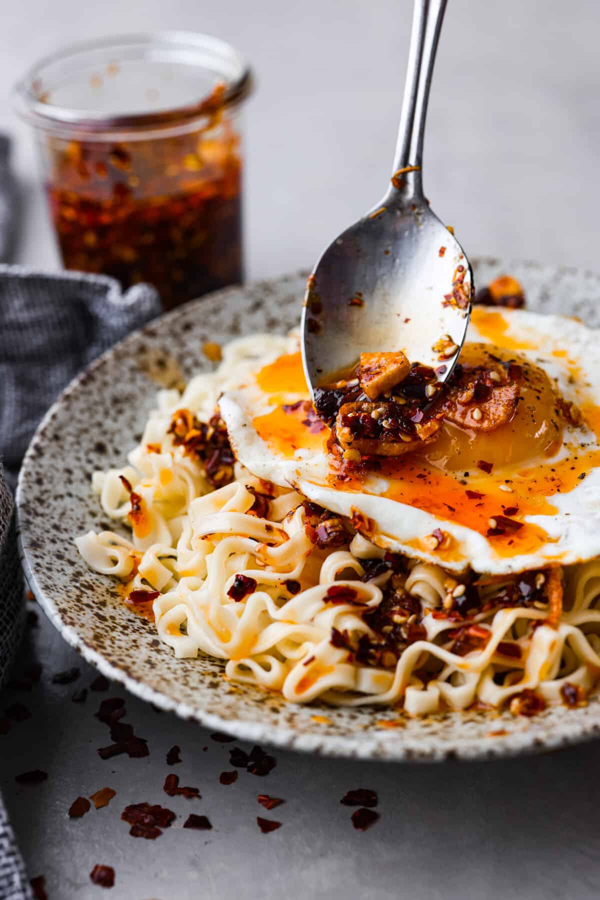 Chili oil being added to an egg and noodle dish.