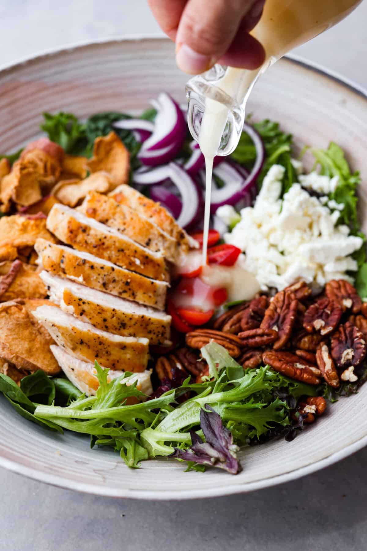 Pouring the vinaigrette over the fuji apple chicken salad.